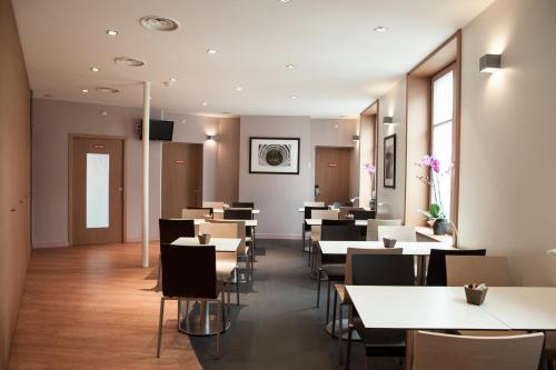 uma sala de jantar com mesas e cadeiras brancas em ibis Lille Centre Grand Place em Lille