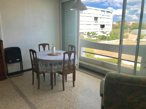 una sala da pranzo con tavolo, sedie e finestra di AS17378 - P4 Dans une résidence sur la plage avec vue mer et piscine a Le Grau-du-Roi