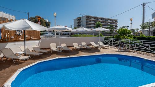 una piscina con sillas, mesas y sombrillas en Marine Congo Hotel en Rodas