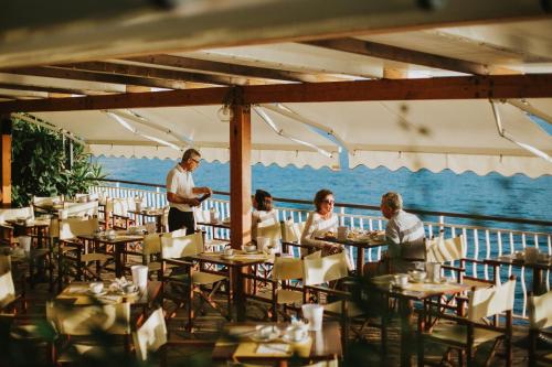 een groep mensen die aan tafel zitten in een restaurant bij Hotel Arc En Ciel in Diano Marina