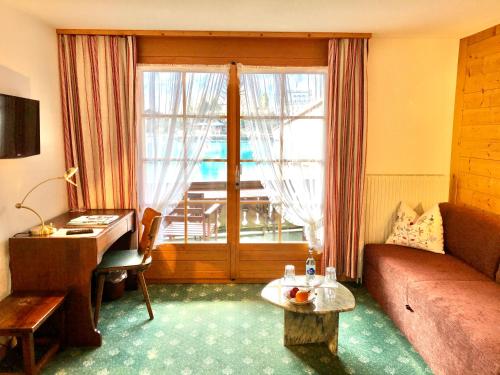 uma sala de estar com um sofá, uma secretária e uma janela em Hotel Châlet Du Lac em Iseltwald