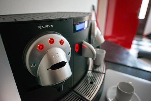 a coffee machine with aucer and cups at PB Urban Garden Stay with secured Parking in Sremska Mitrovica