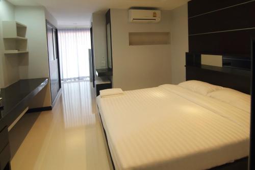 a large white bed in a room with a window at Smith Residence in Suratthani
