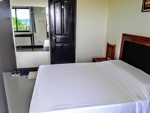 a bedroom with a white bed and a mirror at Adayo Cove Resort in Siquijor