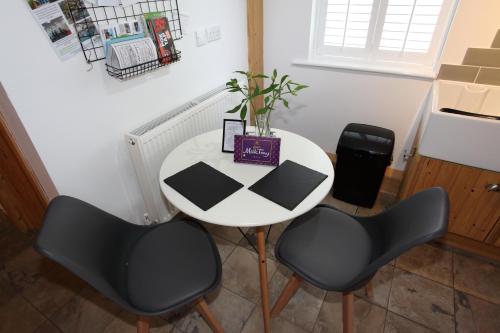 a white table and two chairs in a kitchen at Lynton Lodge Studios in Keswick