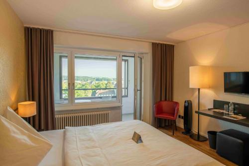a bedroom with a bed and a window at HOTEL illuster - Urban & Local in Uster