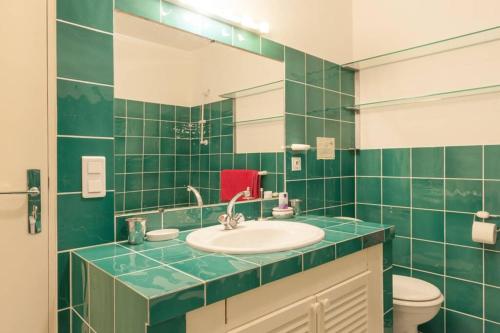 La salle de bains carrelée de couleur verte est pourvue d'un lavabo et de toilettes. dans l'établissement Villa Pétale de Rose, à Cavalaire-sur-Mer