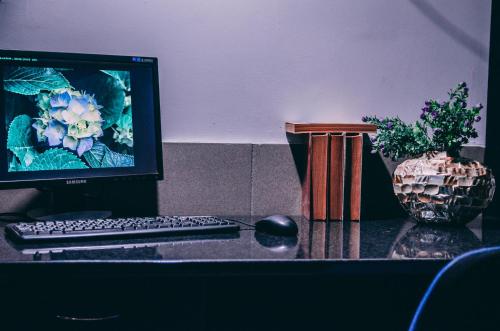 a computer monitor and a keyboard and a vase on a desk at Smart Hostel in Odesa