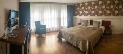 a bedroom with a bed and a desk and a window at B&B Posthoorn in Hoorn