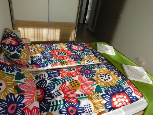 a bed with a blanket with flowers on it at Katamaran in Siófok