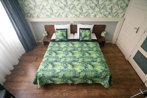 a bedroom with a bed with a green blanket and pillows at B&B Posthoorn in Hoorn