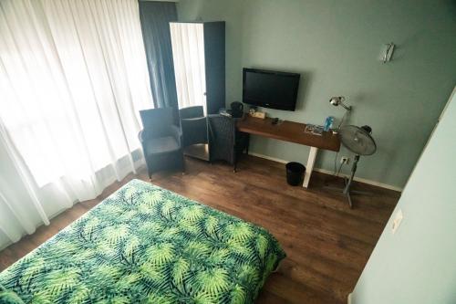 a room with a television and a desk with a bed at B&B Posthoorn in Hoorn