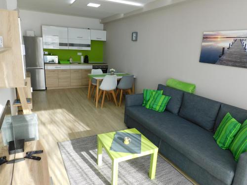 a living room with a blue couch and a kitchen at Katamaran in Siófok