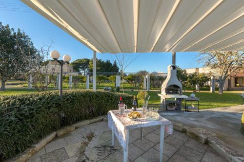a patio with a table and a grill under a canopy at Casina Farnarari by BarbarHouse in Monteroni di Lecce
