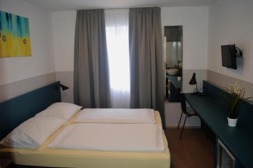 a bedroom with a bed and a desk with a window at Pension Elisabeth - Rooms & Apartments in Salzburg