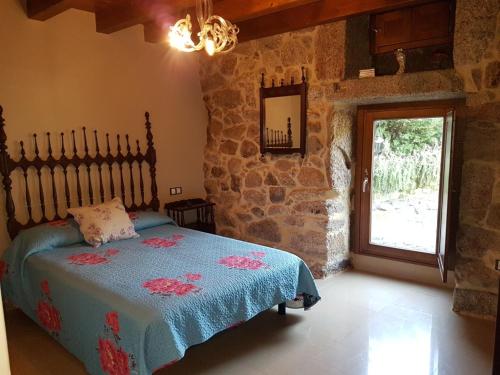 a bedroom with a bed and a stone wall at CAPELA DA GRANXA in Pontevedra