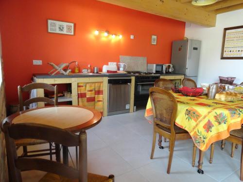 a kitchen with a table and a kitchen with orange walls at Ferme Passion in Saint-Trivier-sur-Moignans