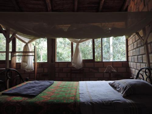 1 dormitorio con 1 cama en una habitación con ventanas en Mishky Wasi, en Lamas