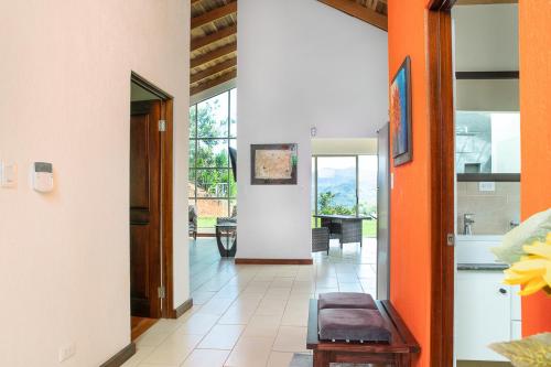 a hallway with orange walls and aoyer with a table at Casa Sofia, a Gem Close to Orosi Thermal Pools! in Orosí