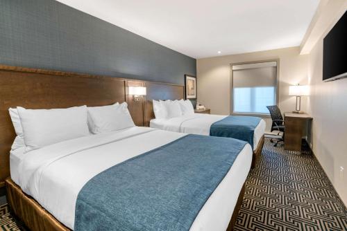 a hotel room with two beds and a television at Quality Inn Centre-Ville in Montreal