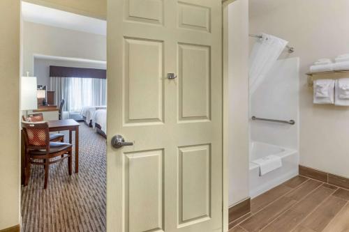 a door to a room with a bed and a bathroom at Quality Inn & Suites University Fort Collins in Fort Collins