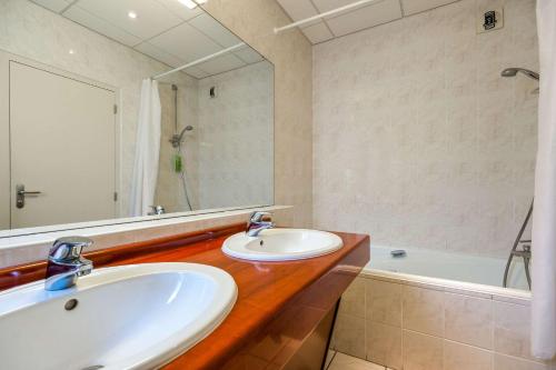 a bathroom with two sinks and a bath tub at Quality Hotel Pau Centre Bosquet in Pau