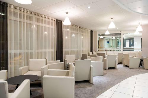 a waiting room with white chairs and tables at Quality Hotel Pau Centre Bosquet in Pau
