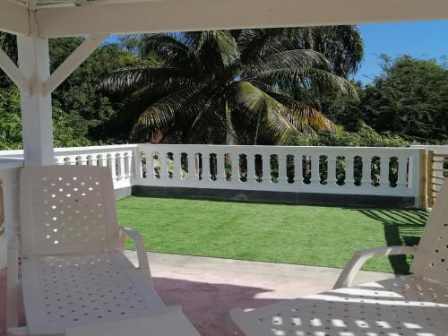 a white fence on a yard with chairs and grass at House Jardin Del Caribe in Las Terrenas