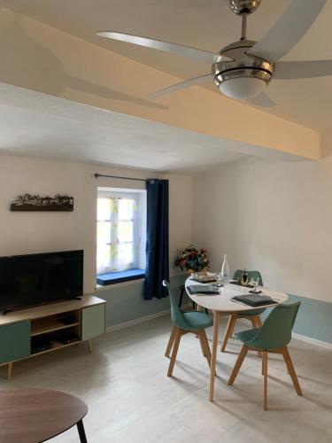 un salon avec une table, des chaises et une télévision dans l'établissement Jolie Vue Cité, aux pieds des remparts, à Carcassonne