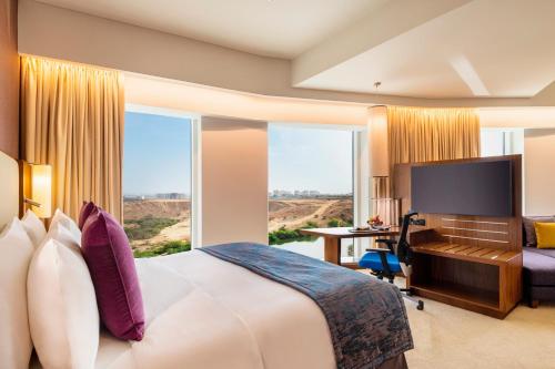 a hotel room with a bed and a desk and a large window at Crowne Plaza Muscat OCEC by IHG in Muscat