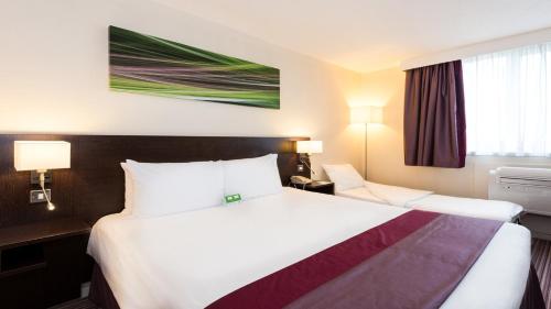 a hotel room with a large bed with white sheets at Holiday Inn Slough Windsor by IHG in Slough