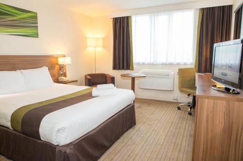 a hotel room with a bed and a flat screen tv at Holiday Inn Slough Windsor by IHG in Slough