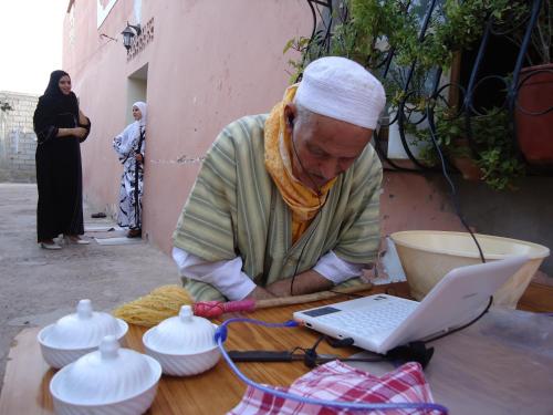 a man sitting at a table with a laptop computer at Takad Dream Rural in Takate