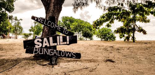 a street sign on a beach next to a tree at Salili Bungalow in Gili Air