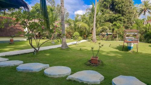 a park with rocks in the grass with palm trees at Salili Bungalow in Gili Air
