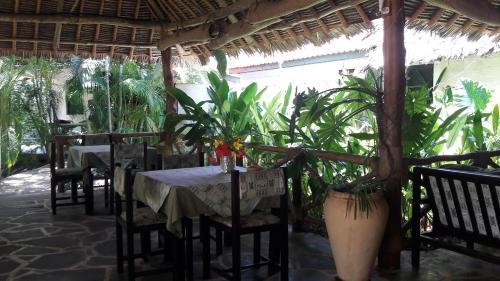 
a patio area with tables, chairs and umbrellas at African Dream Cottages - Diani Beach in Diani Beach
