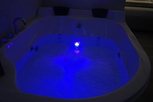 uma banheira de hidromassagem azul num quarto escuro em B&B Maison Grace em Peschici
