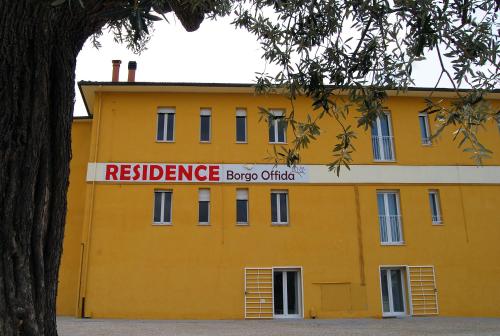 a yellow building with a red sign on it at Residence Borgo Offida in Offida