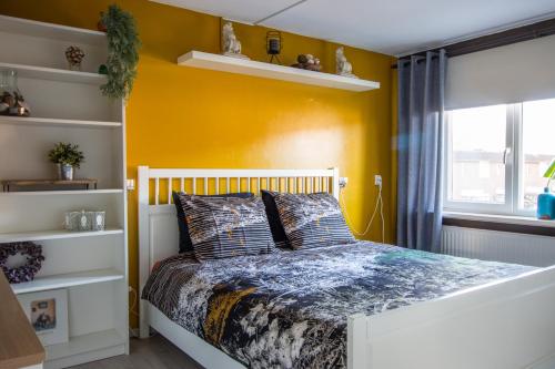 um quarto com uma cama e uma parede amarela em CasaLuca em Hellevoetsluis