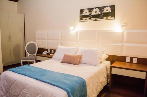 una camera da letto con un letto con lenzuola e cuscini bianchi di POUSADA ESTÂNCIA a Penedo
