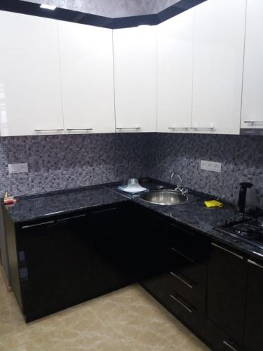 a kitchen with black counter tops and white cabinets at Apartments Niagara Gyumri in Gyumri
