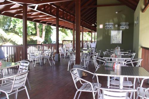 an empty restaurant with tables and white chairs at Surfers Beach Self Catering Chalets in Takamaka