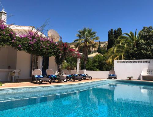 a swimming pool with chairs and purple flowers next to a building at Charming Villa with Heated Pool near Sandy Beach, Hiking, Golf and Wineries in Luz