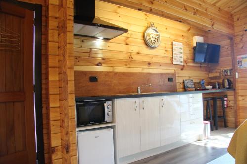 una cocina con armarios blancos y un reloj en la pared en Sunset Chalet, en Lake Tekapo