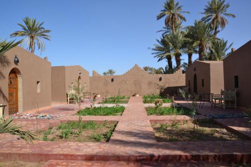 a garden in the middle of a building with palm trees at Mhamid Auberge Saharaespace in Mhamid