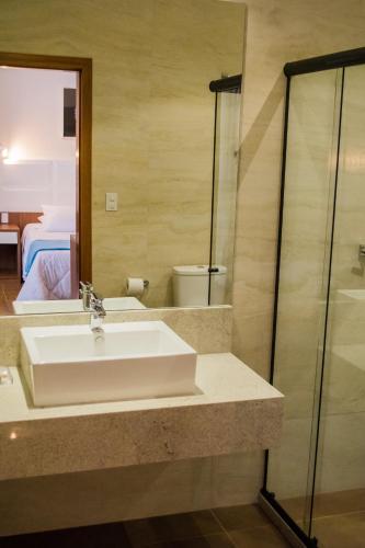 a bathroom with a white sink and a shower at POUSADA ESTÂNCIA in Penedo