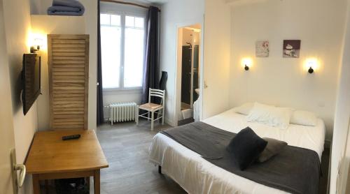 Un dormitorio con una cama y una mesa. en Les Chiens du Guet en Saint-Malo