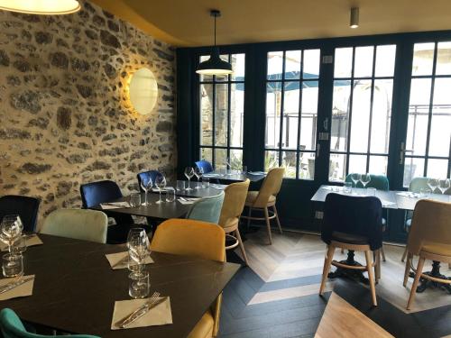 uma sala de jantar com mesas, cadeiras e janelas em Les Chiens du Guet em Saint Malo