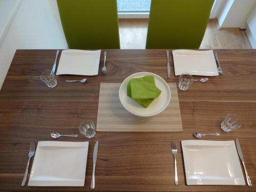 a wooden table with a white plate and silverware at "NATURE erLeben" Appartement & Komfortzimmer in Velden am Wörthersee