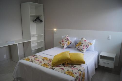 uma cama branca com almofadas num quarto em Ventura Hotel em Barreiras